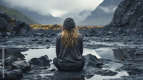 a grieving sad young woman crouches on a mountain amidst clouds