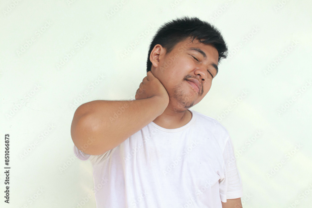 Tired upset young man wears white t-shirt suffering from pain, muscle spasm at workplace. Fatigue, deadline, pain and incorrect posture. Tired upset young man wears white t-shirt suffering from pain, muscle spasm at workplace. Fatigue, deadline, pain and incorrect posture.