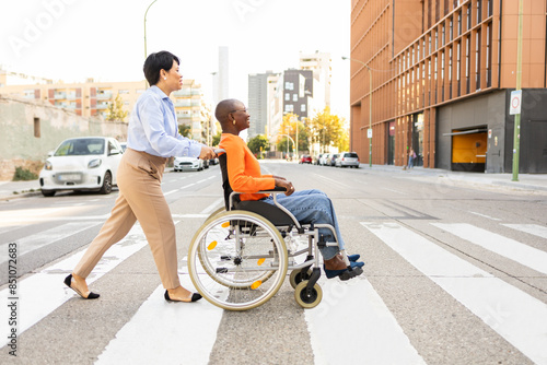 Supportive businesswoman assisting colleague in wheelchair photo