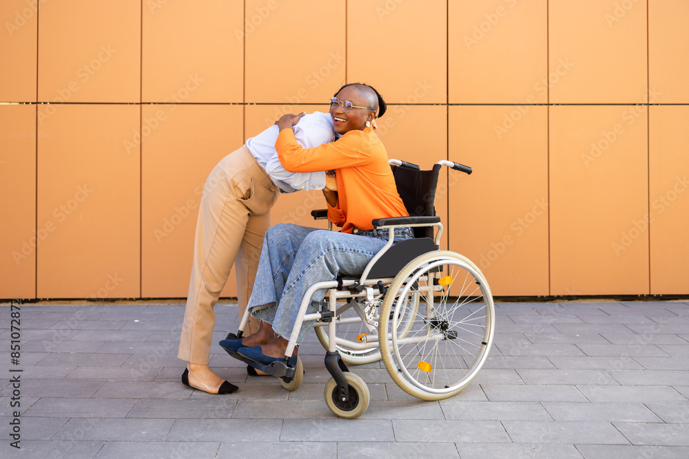Businesswoman in wheelchair being embraced by colleague Businesswoman in wheelchair being embraced by colleague