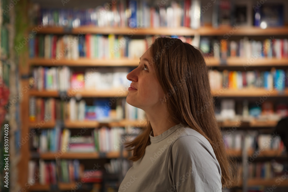 Young Woman Looking Up in Book-Filled Library Young Woman Looking Up in Book-Filled Library