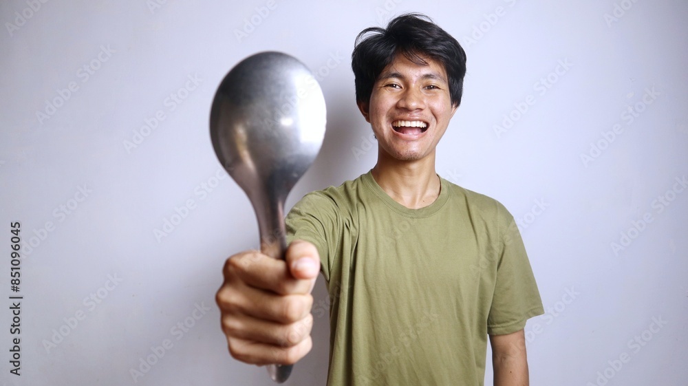 excited young asian man gesturing holding a big spoon excited young asian man gesturing holding a big spoon