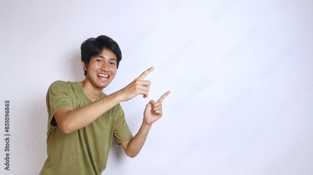 excited young asian man pointing to the side on isolated white background excited young asian man pointing to the side on isolated white background