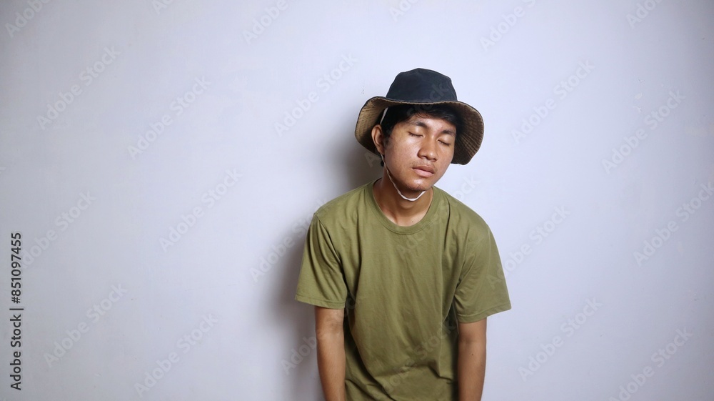 young asian man wearing a hat lethargic, tired hunched posture young asian man wearing a hat lethargic, tired hunched posture