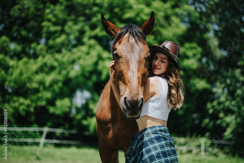 A young woman bonding with her horse in a lush green countryside setting, enjoying outdoor life and nature on a sunny day.
