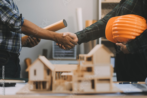 Architect and construction engineer holding hands while working for teamwork and cooperation concept after completing an agreement at construction site, office, close-up image photo