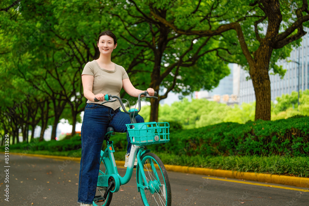 Obraz premium Woman Riding Bicycle in Green Urban Park