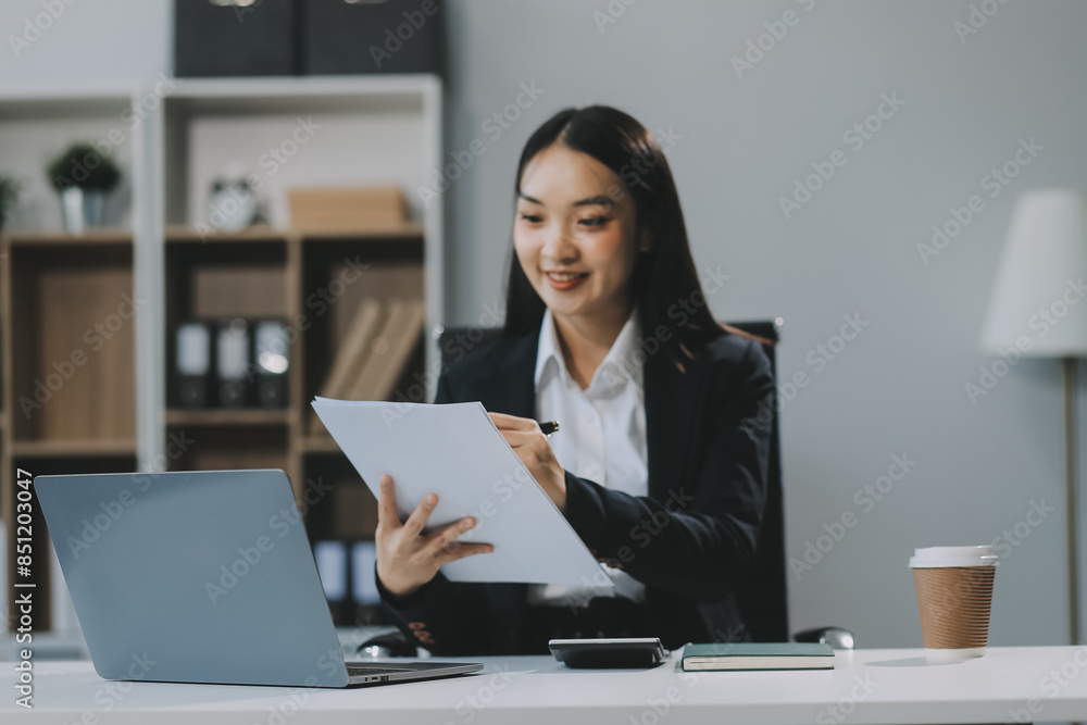 Happy young Asian businesswoman working on laptop and taking notes In office. Happy young Asian businesswoman working on laptop and taking notes In office.