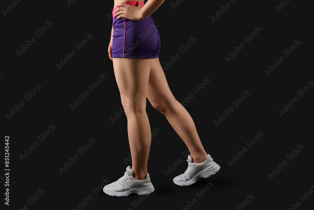 Sporty young woman in shorts on black background Sporty young woman in shorts on black background