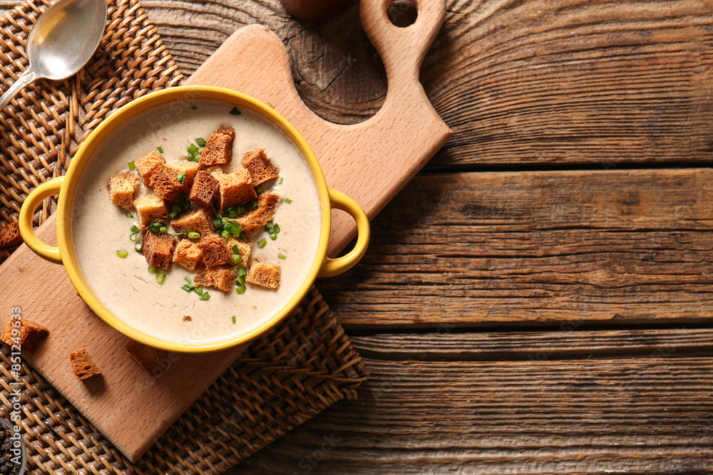 Pot of tasty cream soup with croutons on wooden background Pot of tasty cream soup with croutons on wooden background