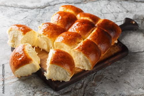 Obraz na płótnie Homemade Freshly baked soft Dinner Rolls or Hawaiian Buns closeup on the wooden board on the table. Horizontal w salonie