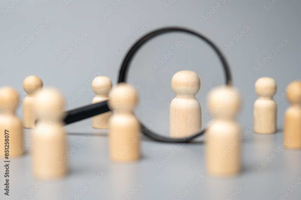 Obraz premium Wooden dolls and magnifying glass. Talent acquisition, recruitment and hiring concept.