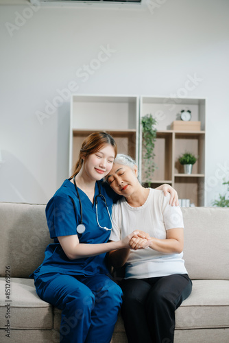 Asian caregiver doctor examine older patient woman therapist nurse at nursing home taking care of senior elderly woman sit on sofa.Medical service concept. photo