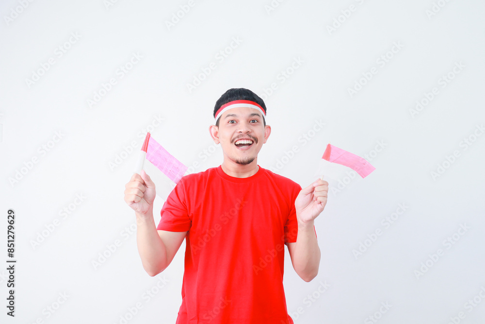 Excited young Asian man celebrate Indonesian independence day on 17 August by holding the Indonesian flag isolated over white background Excited young Asian man celebrate Indonesian independence day on 17 August by holding the Indonesian flag isolated over white background