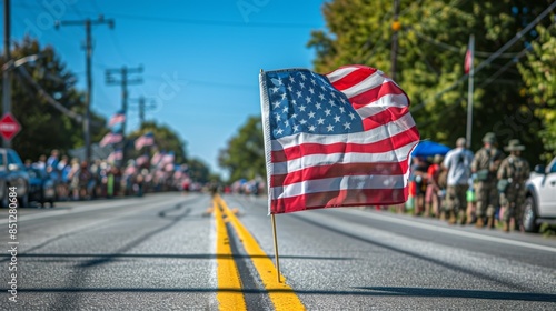 An American flag waving proudly in a parade with a crowd of people and cars in the background. photo