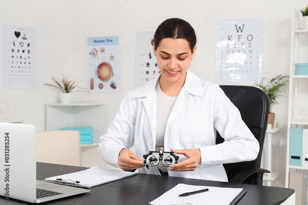 Female ophthalmologist with trial frame sitting at table in clinic Female ophthalmologist with trial frame sitting at table in clinic