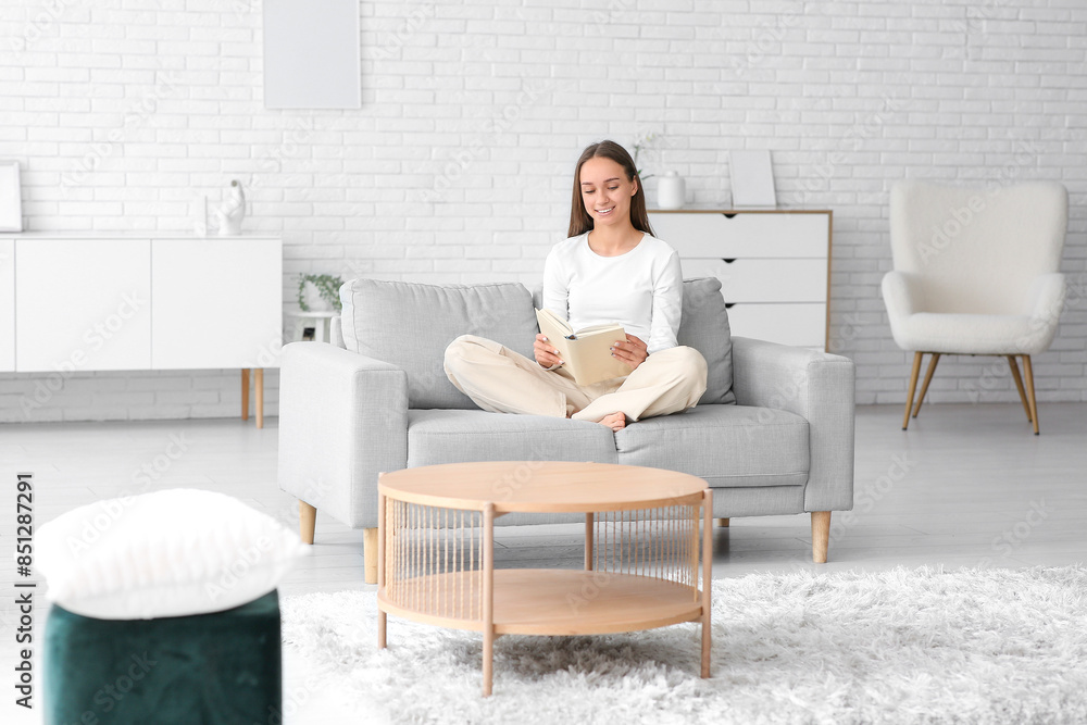 Young pretty woman reading book on cozy couch at home Young pretty woman reading book on cozy couch at home
