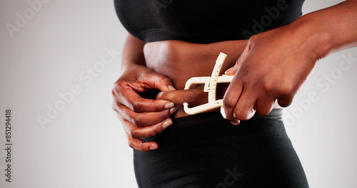 African woman using a fat caliper to measure belly fat, focusing photo