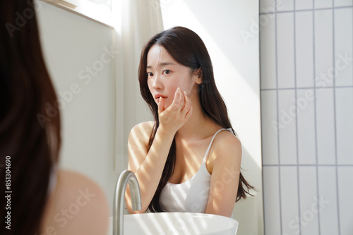鏡の前でスキンケアをする若いアジア人女性