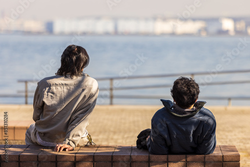 Foto 休憩時に港で海を眺める男性作業員の後ろ姿