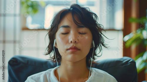 Pretty asian woman with headphones listening comfortably to relaxing music podcast app at home studio.