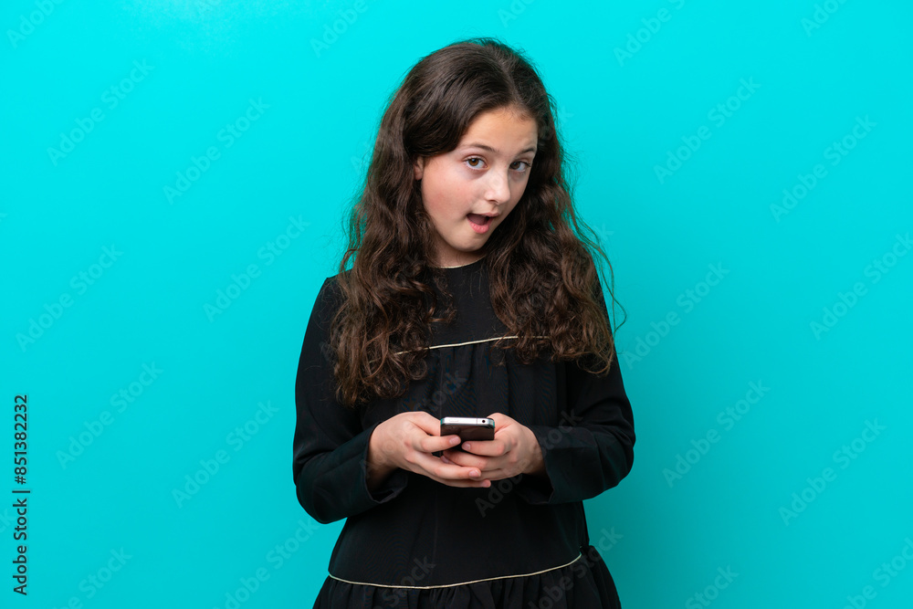 Little girl isolated on blue background surprised and sending a message Little girl isolated on blue background surprised and sending a message