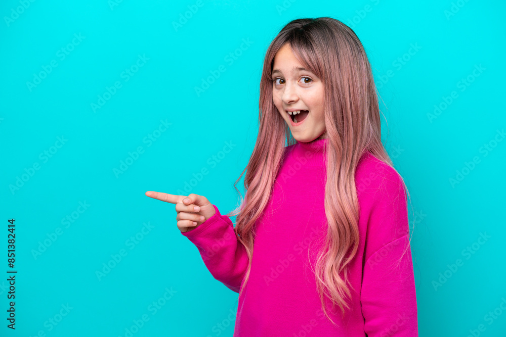 Little girl with pink hair isolated on blue background surprised and pointing finger to the side Little girl with pink hair isolated on blue background surprised and pointing finger to the side