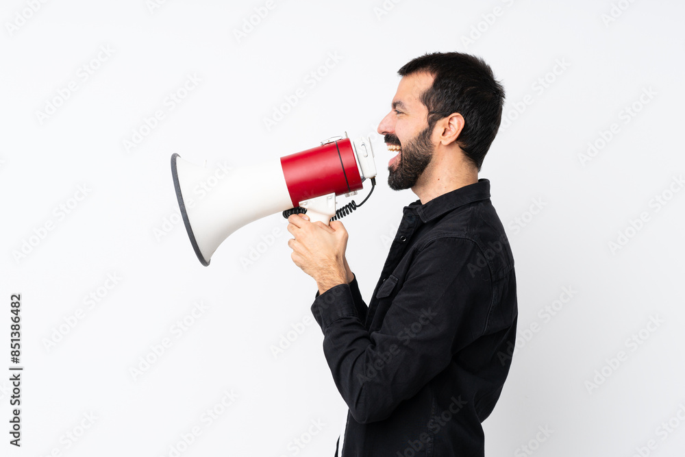 Young man with beard over isolated white background shouting through a megaphone Young man with beard over isolated white background shouting through a megaphone