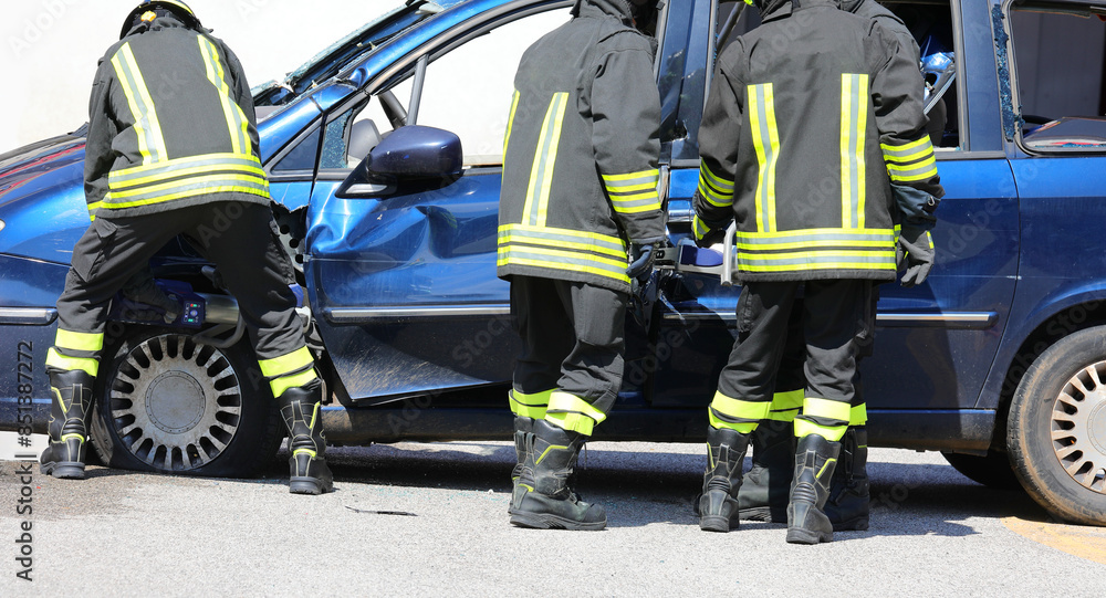 team of firefighters using hydraulic shears and jaws of life to pry open the door of a crashed car after an accident team of firefighters using hydraulic shears and jaws of life to pry open the door of a crashed car after an accident
