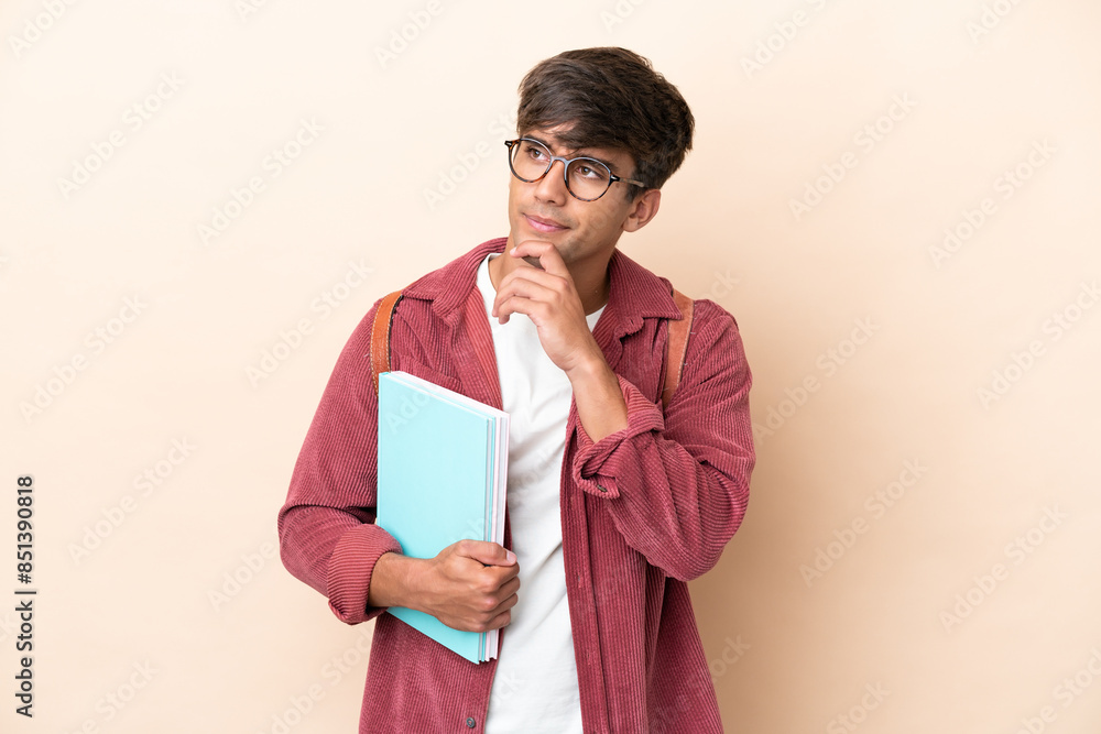 Young student caucasian man isolated on ocher background and looking up Young student caucasian man isolated on ocher background and looking up