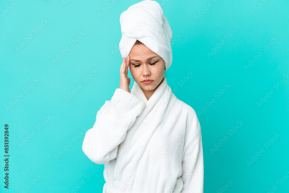Teenager blonde girl in a bathrobe over isolated blue background with headache Teenager blonde girl in a bathrobe over isolated blue background with headache