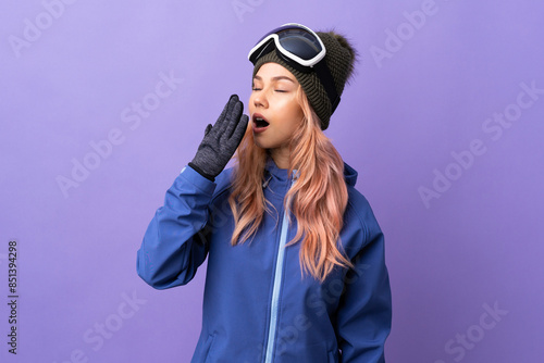 Skier teenager girl with snowboarding glasses over isolated purple background yawning and covering wide open mouth with hand
