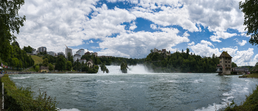 Large panorama of the Rhine Falls with lots of water under blue sky with clouds from the Schaffhausen side Large panorama of the Rhine Falls with lots of water under blue sky with clouds from the Schaffhausen side