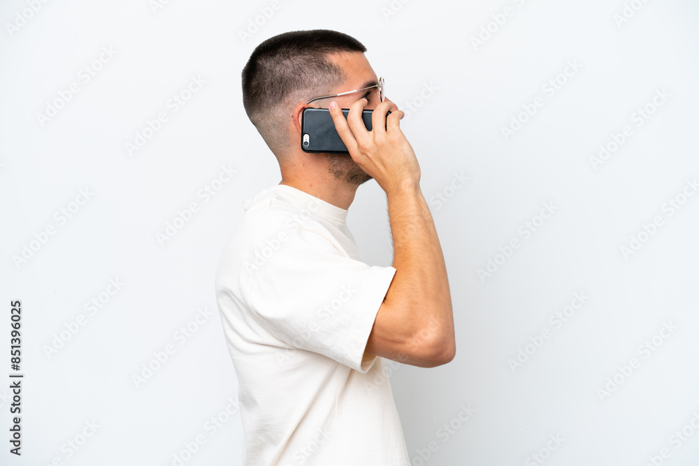 Young caucasian man isolated on white background keeping a conversation with the mobile phone with someone Young caucasian man isolated on white background keeping a conversation with the mobile phone with someone