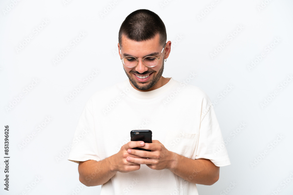 Young caucasian man isolated on white background sending a message or email with the mobile Young caucasian man isolated on white background sending a message or email with the mobile