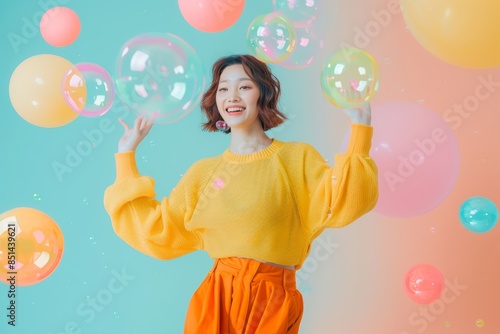 Cute happy young woman in a yellow sweater with colorful bubbles floating above her head isolated on a light turquoise background,