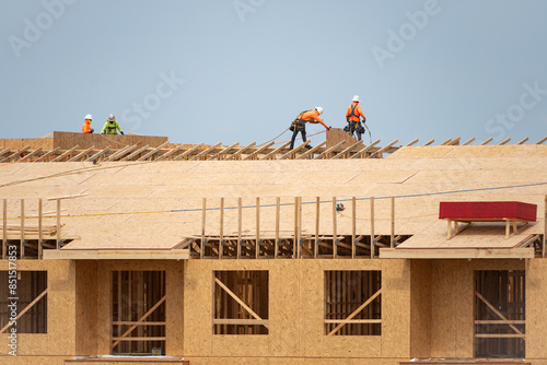 Roof construction. Roofer on roof structure. Construction Worker on Top of the Wooden House Frame. Worker roofer builder working on roof at construction site. Construction crew working on the roof.