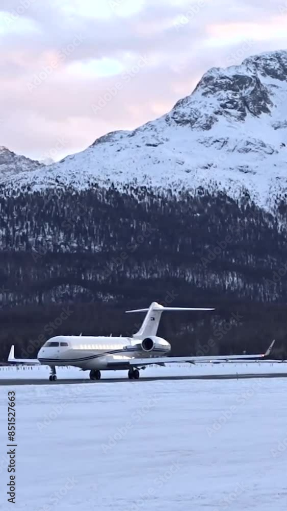High End Long Range Business Jet waiting for take off departure static shot mountain background snow white covered winter landscape High End Long Range Business Jet waiting for take off departure static shot mountain background snow white covered winter landscape