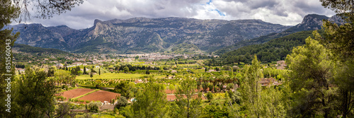 Panoramic view of the verdant Sóller valley seen from GR-221 hiking trail amidst Serra de Tramuntana mountain range in Mallorca, perfect for nature tourism, hiking adventures and springtime travel.