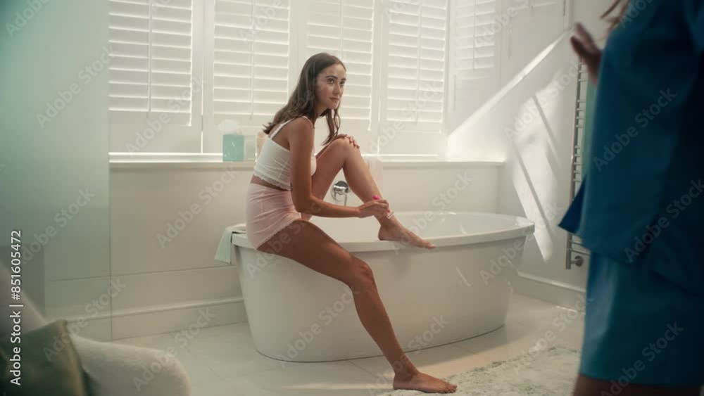 Girl shaving her leg in the bathroom with her friend Girl shaving her leg in the bathroom with her friend