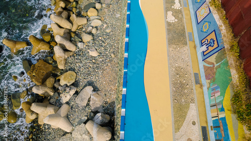 an aerial view of Huinnyeoul Culture Village in Busan, Korea. It showcases a coastal area with distinct blue pathways, artistic murals, and a beautiful shoreline. photo