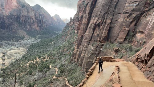 A female hiker walks along the switchbacks of the West Rim Trail in Zion National Park with stunning views of the canyon below. This trail leads to famous Angels Landing - Utah, USA