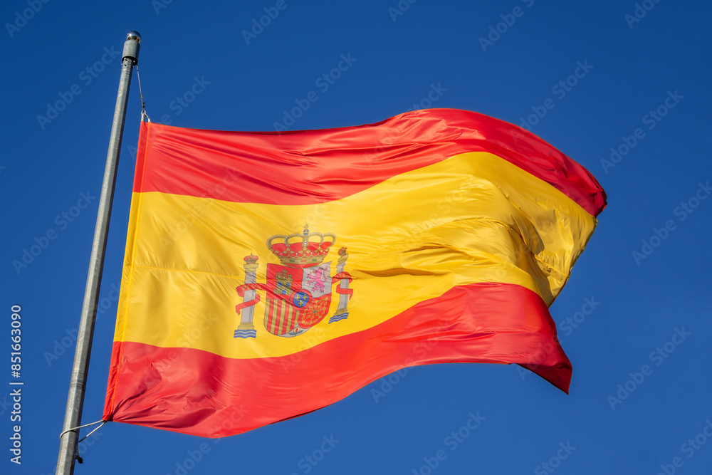 A Spanish flag is waving in the the blue sky A Spanish flag is waving in the the blue sky