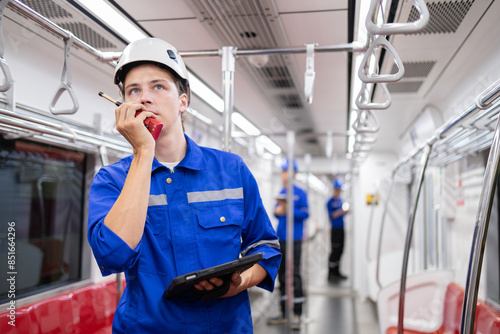 Portrait of young engineer of electric locomotive holding tablet in train