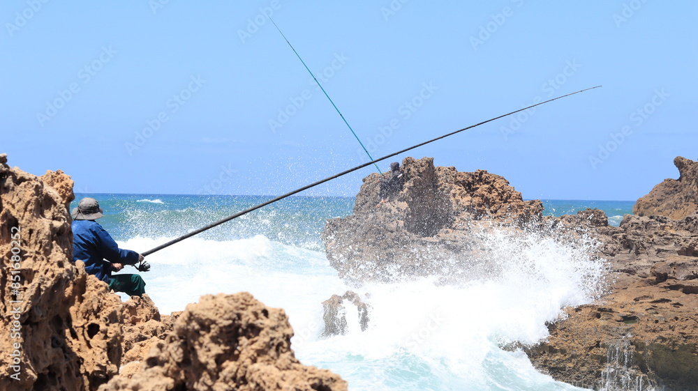 Fisherman on Rocky Shore with Ocean Waves Crashing Fisherman on Rocky Shore with Ocean Waves Crashing