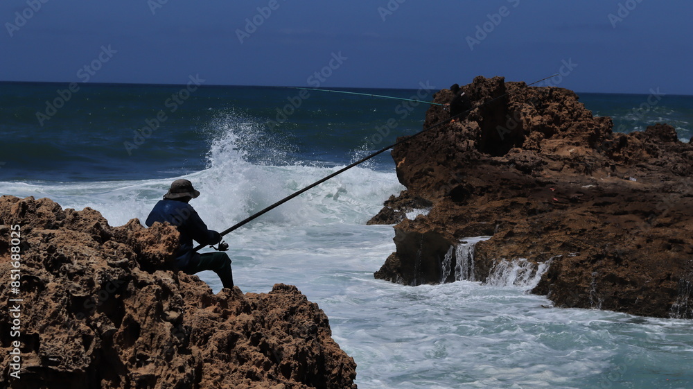 Fisherman on Rocky Shore with Ocean Waves Crashing Fisherman on Rocky Shore with Ocean Waves Crashing