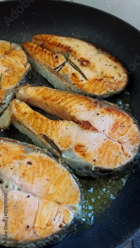 Salmon steak is placed on a frying pan and fried. Slow motion video of cooking diet fish in the kitchen at home.