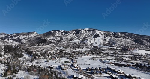 epic wide shot of mountain town during winter covered in snow during a bright blue day in colorado