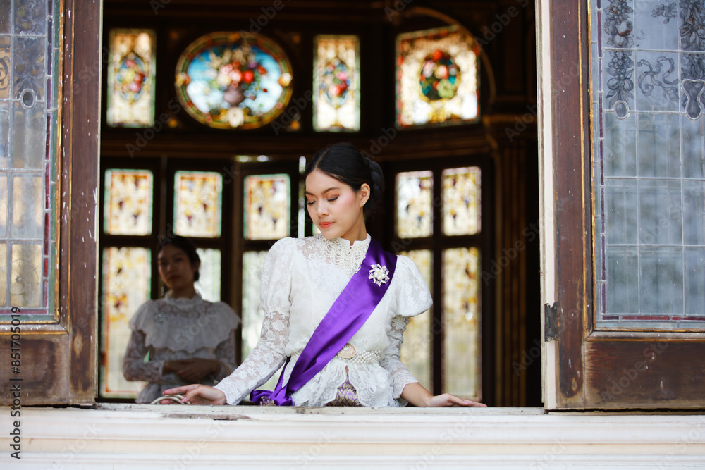 Beautiful Thai girls in traditional Thai costumes Standing in the ancient window in Thailand.Portrait of Beautiful woman wearing traditional Thai culture vintage style standing by a window looking out Beautiful Thai girls in traditional Thai costumes Standing in the ancient window in Thailand.Portrait of Beautiful woman wearing traditional Thai culture vintage style standing by a window looking out
