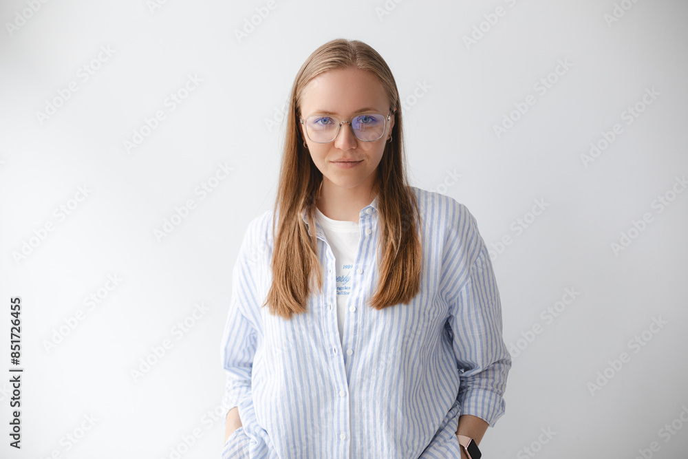 Young blonde woman standing with hands in pockets, wearing white shirt ...